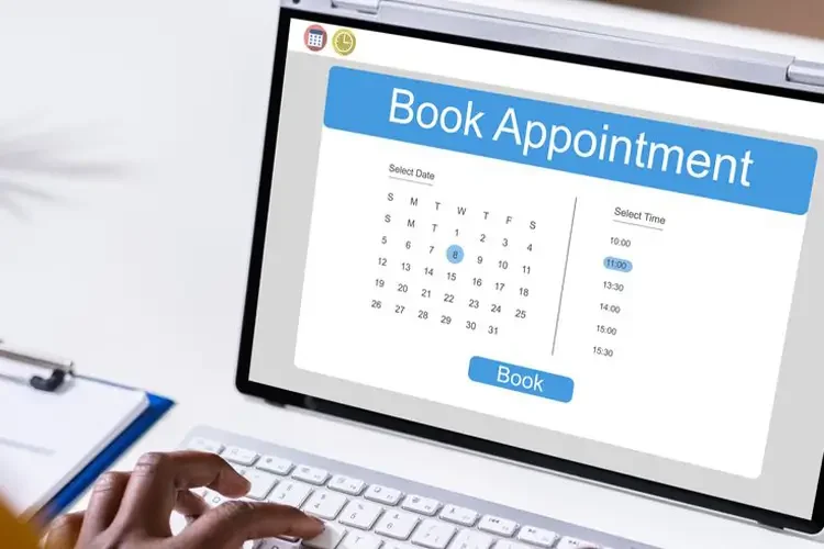 Online appointment booking screen on a laptop with a calendar, time options, and a blue "Book" button.