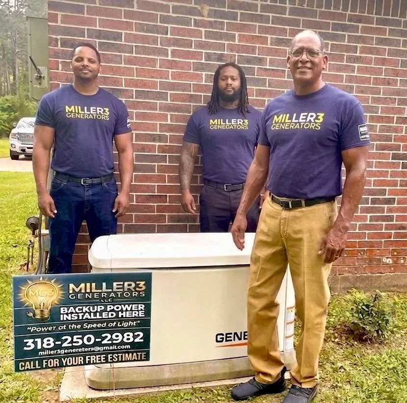 Three men standing outdoors next to a large white generator with a sign. All three are wearing matching navy blue T-shirts with the Miller3 Generators logo. The man on the right is smiling, wearing glasses and beige pants. The other two men are standing behind the generator, one with long dreadlocks and the other with short hair. The sign in front promotes Miller3 Generators, mentions backup power installation, includes a phone number and email for estimates.
