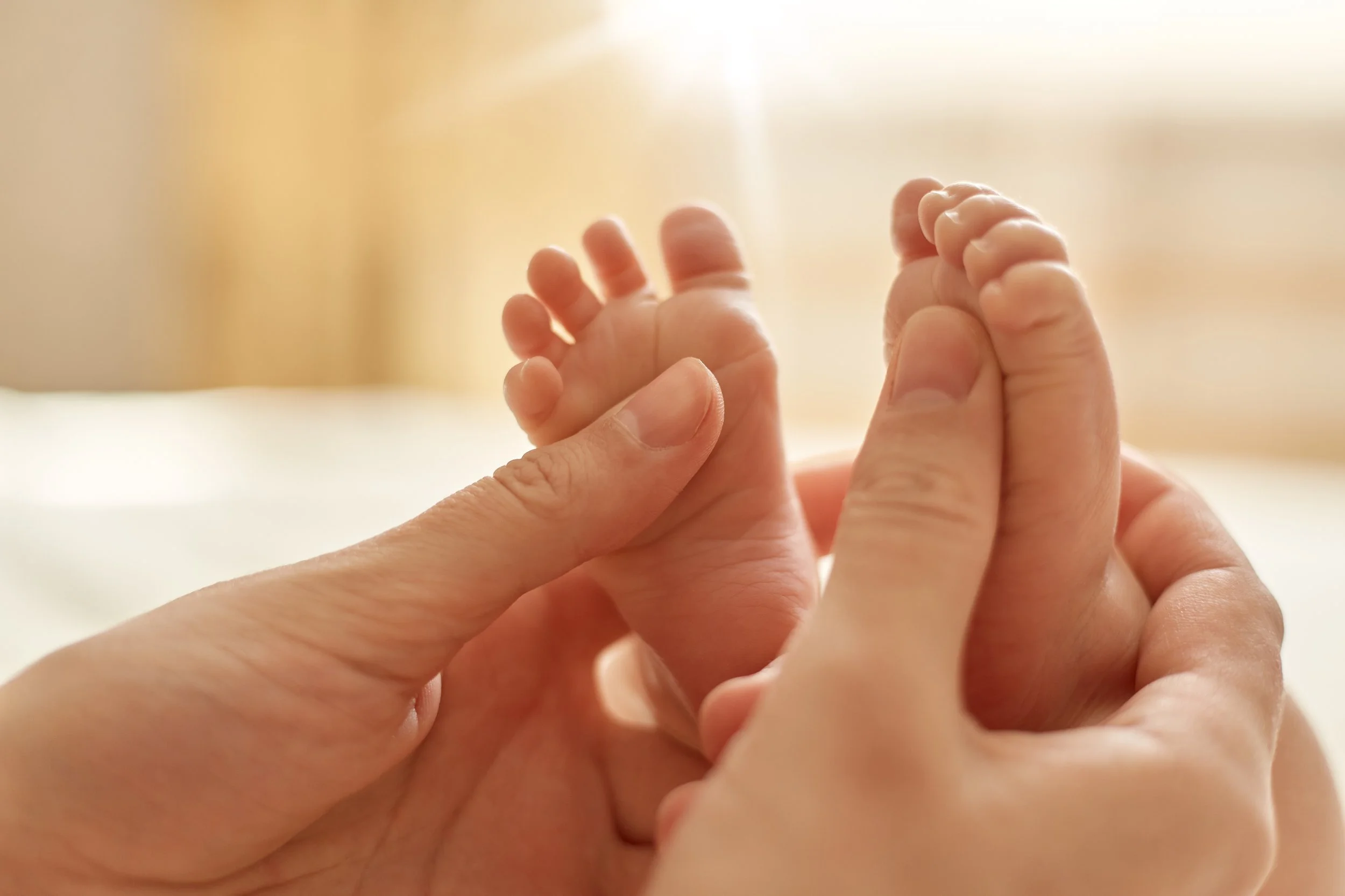 mum-making-baby-massage-mother-massaging-infant-bare-foot-preventive-massage-newborn-mommy-stroking-baby-s-feet-with-both-hands-light-background.jpg