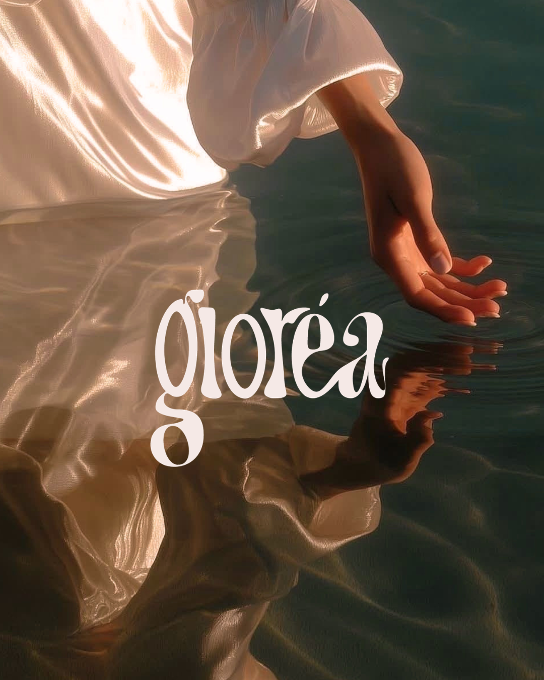 A close-up of a person's hand resting on water, wearing a satin garment, with the word 'göra' overlaid in white text.