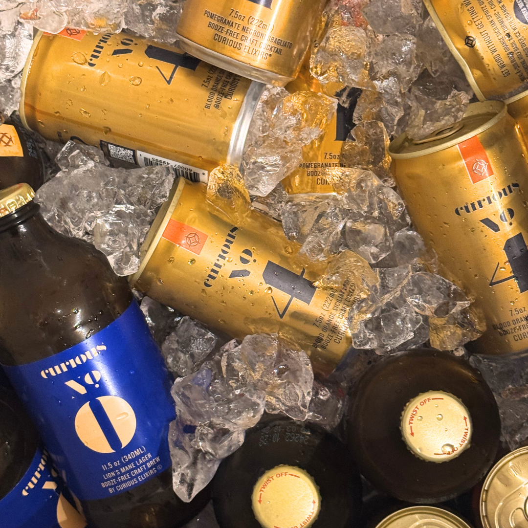 Assorted cans of Curious Elixirs and other beverages chilled on ice.