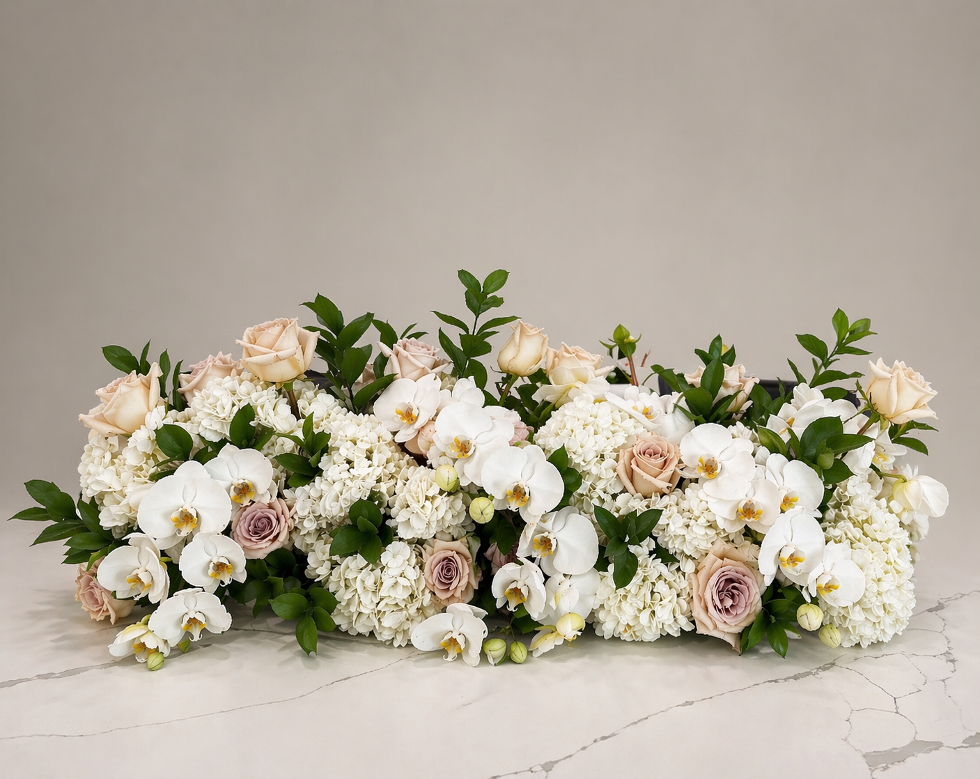 Romantic white rose and orchid arrangement designed with soft neutral tones for elegant weddings and refined events.