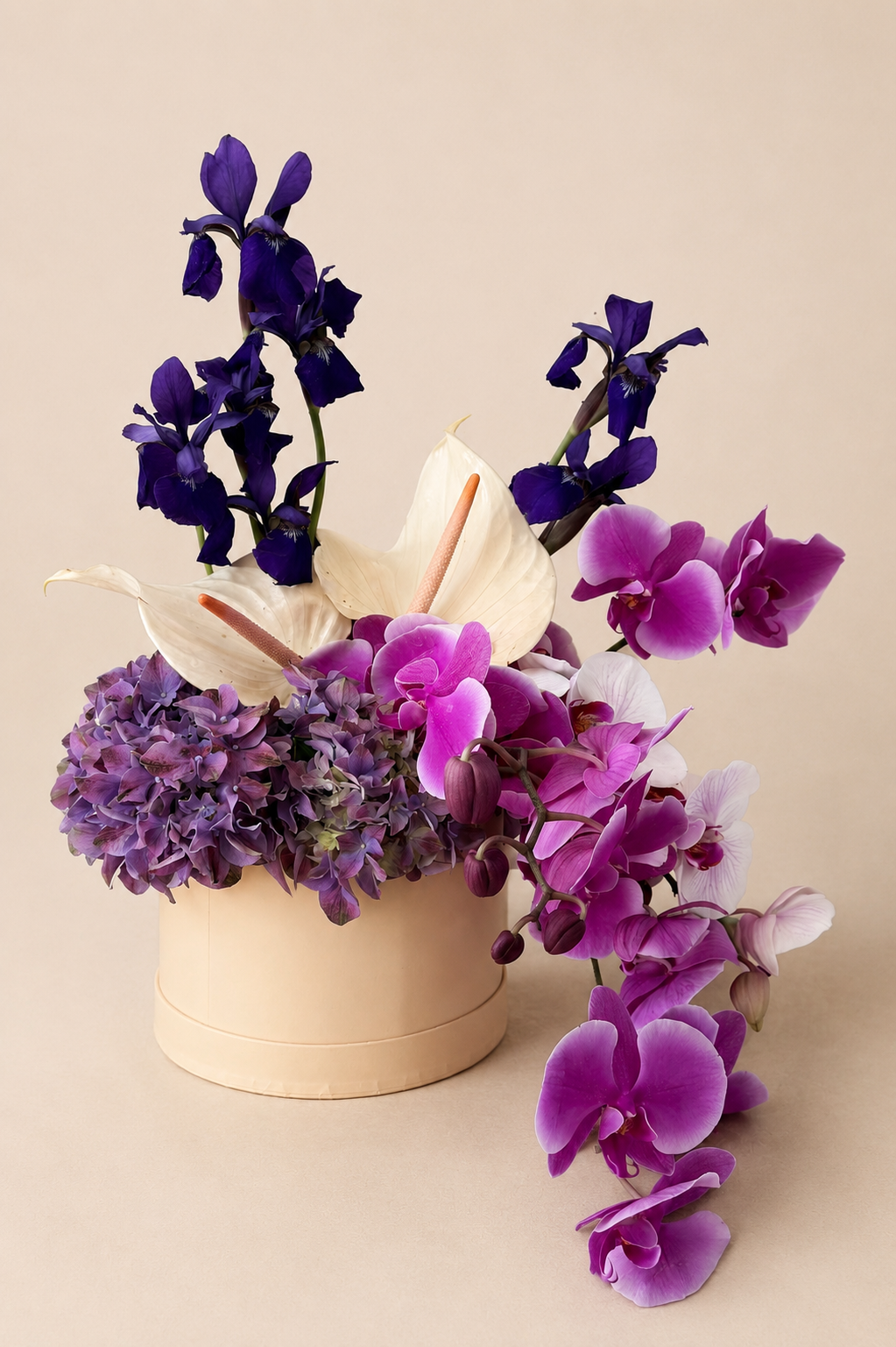 Editorial orchid and hydrangea arrangement with irises and anthuriums in a modern neutral vessel.