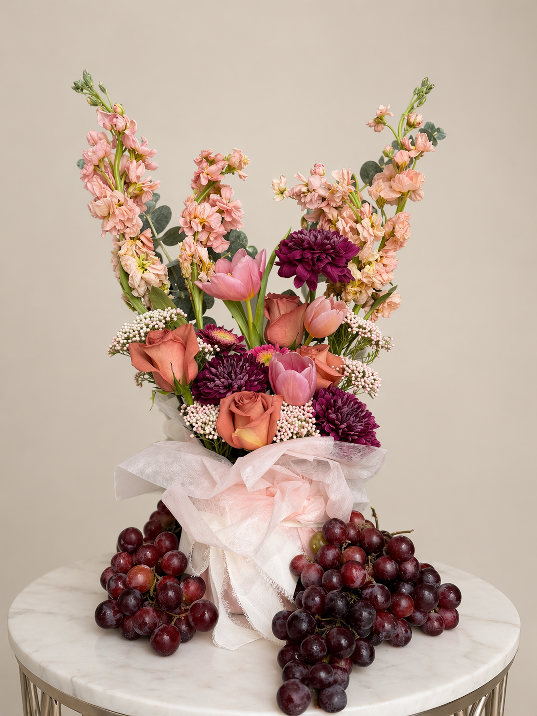 Artistic bouquet with layered peach, blush, and plum florals styled in signature wrap for a luxury presentation.