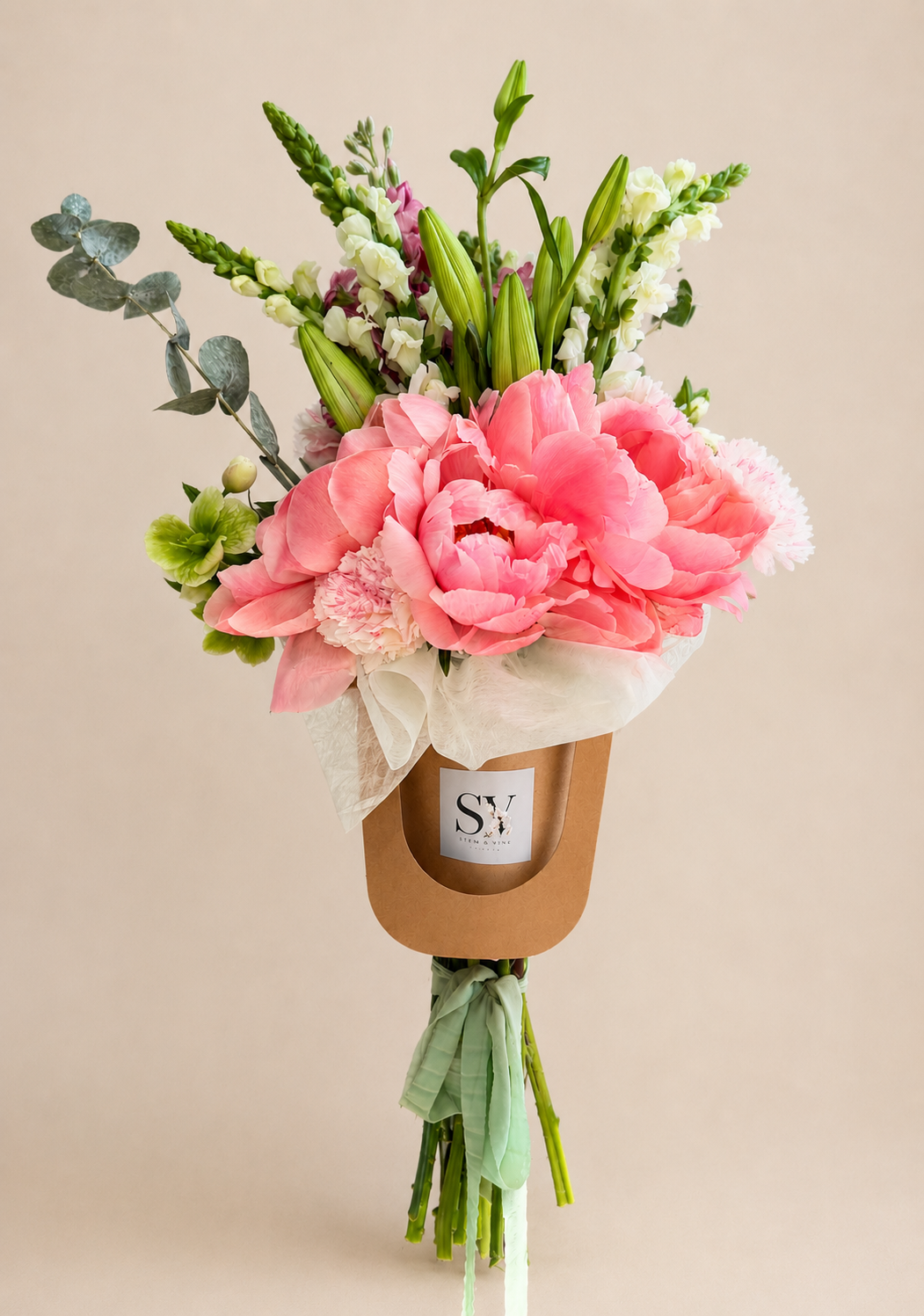 Hand-tied luxury bouquet with peonies and snapdragons wrapped in signature paper by Stem & Vine Studio.