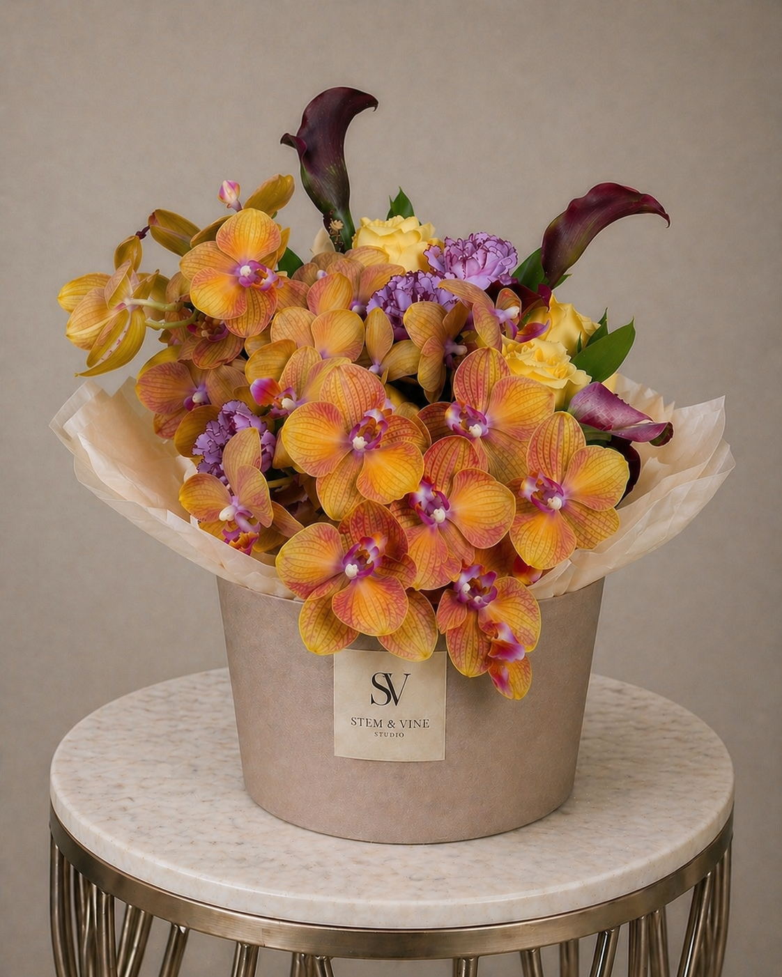 Sculptural orchid arrangement with deep calla lilies and vibrant tropical florals in a contemporary floral box.