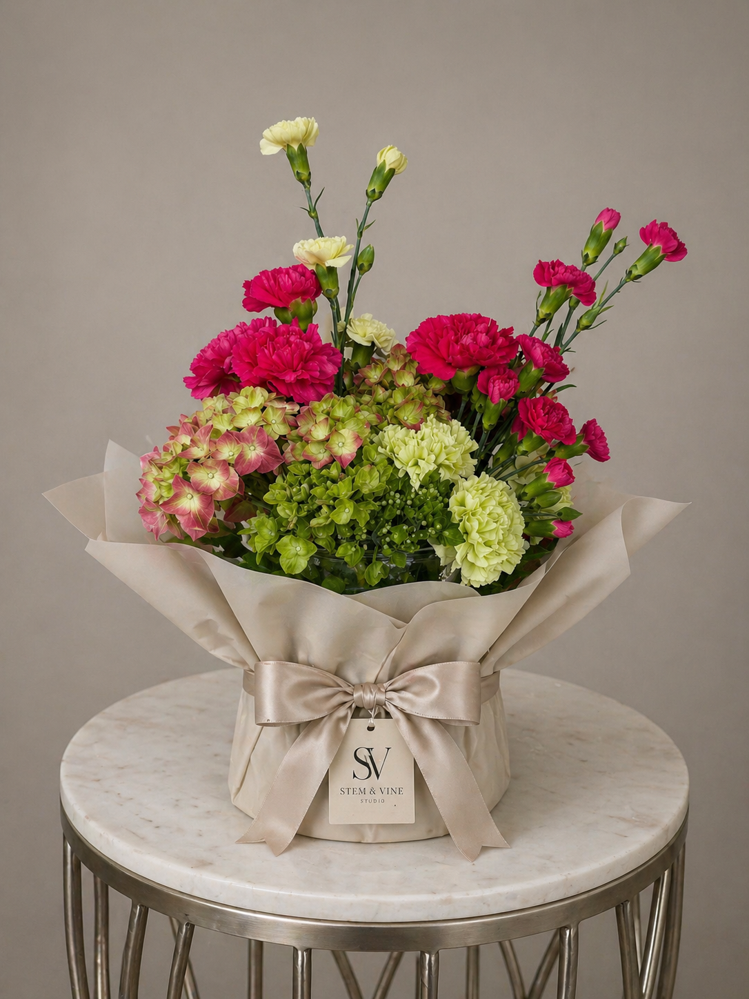 Soft romantic bouquet with roses and seasonal florals wrapped in signature paper by Stem & Vine Studio.