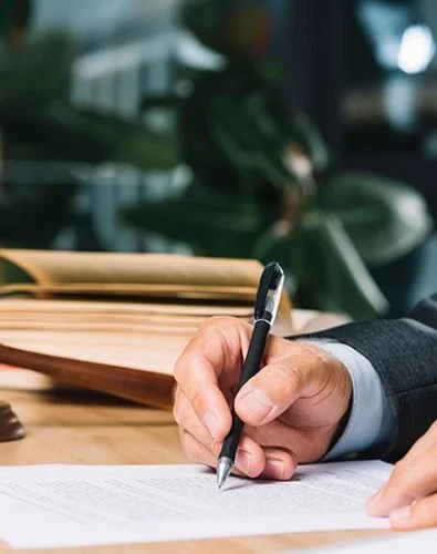 an image of a hand holding a pen signing a paper
