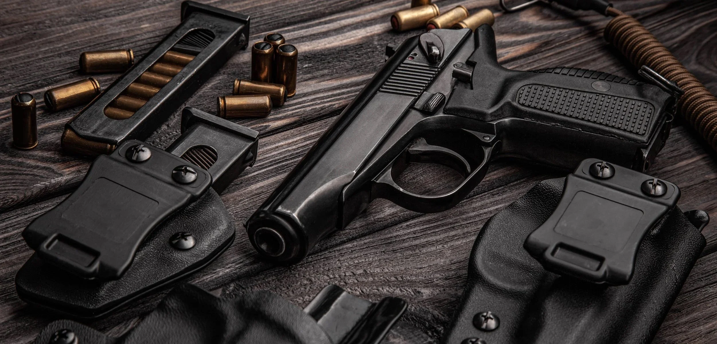A handgun with bullets and ammunition on a wooden surface.