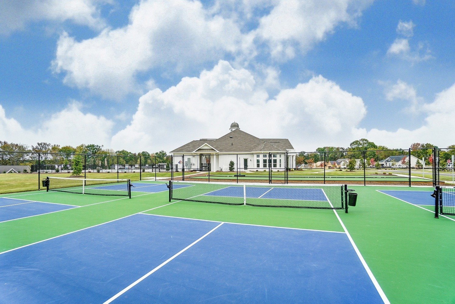 heritage-in-indian-trail-pickleball-courts-with-clubhouse-in-background-active-adult-community-indian-trail-nc.jpg