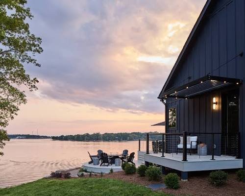 modern-dark-barn-style-lakefront-home-with-dock-and-adirondack-chairs-at-sunset.jpeg