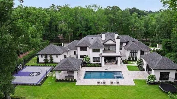 aerial-view-of-white-luxury-estate-home-with-pool-and-manicured-grounds.jpeg