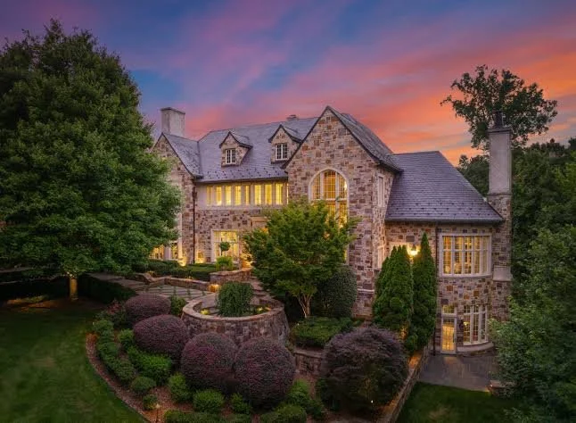 luxury-stone-tudor-style-home-exterior-at-sunset-with-dramatic-pink-sky.jpeg