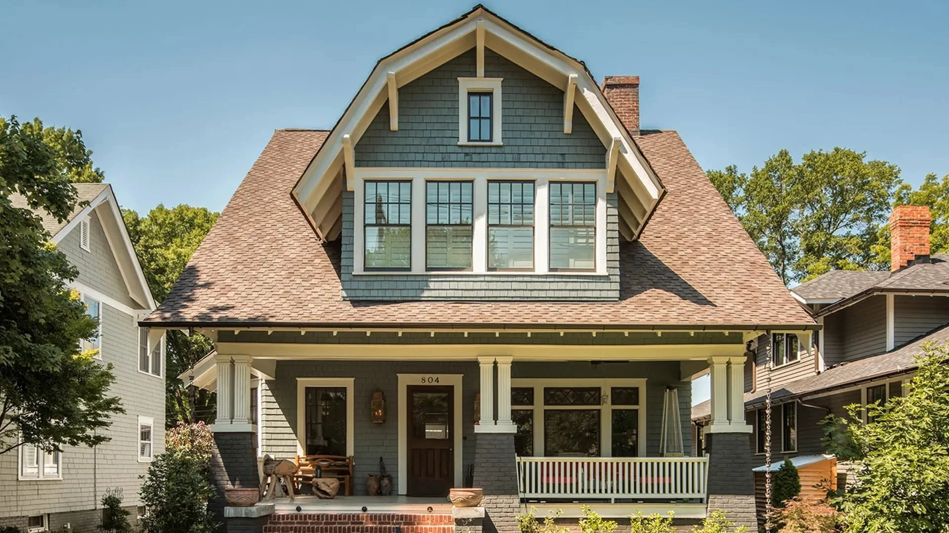 craftsman-style-home-with-dark-green-siding-covered-front-porch-and-dormer-windows.webp