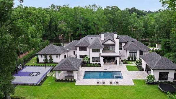 aerial-view-of-white-luxury-estate-home-with-pool-and-manicured-grounds.jpeg