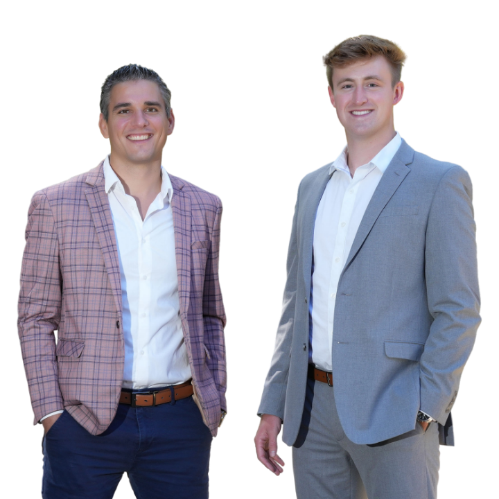 Two young men in suits standing and smiling for a photo.