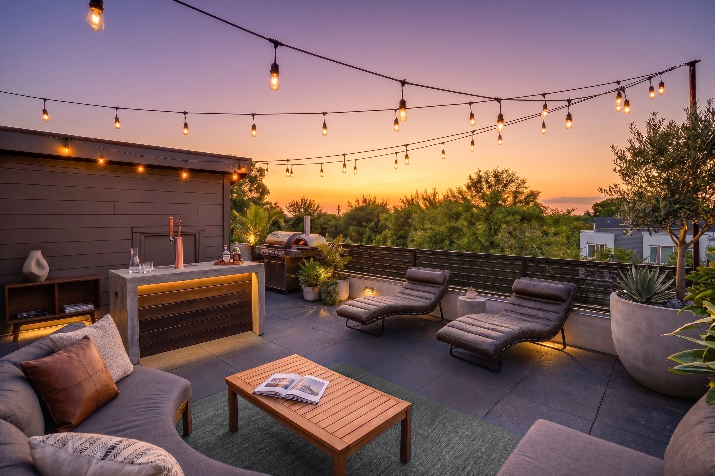 A cozy outdoor rooftop patio at sunset with string lights overhead, a lounge area with cushions and a coffee table, a grill, and lush greenery in the background.