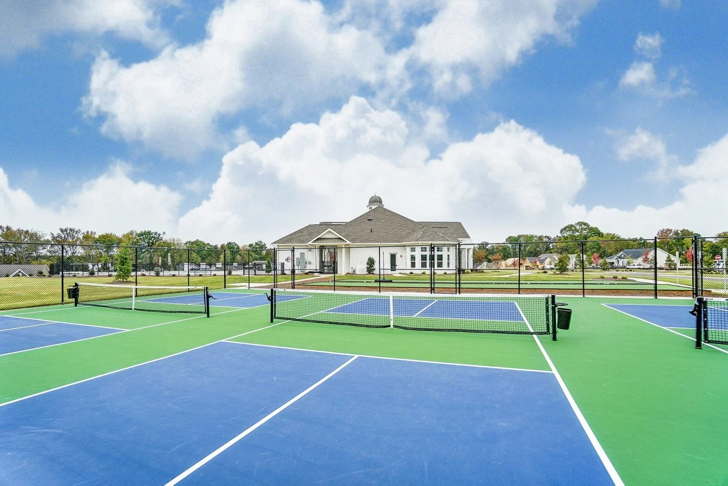 heritage-in-indian-trail-pickleball-courts-with-clubhouse-in-background-active-adult-community-indian-trail-nc.jpg