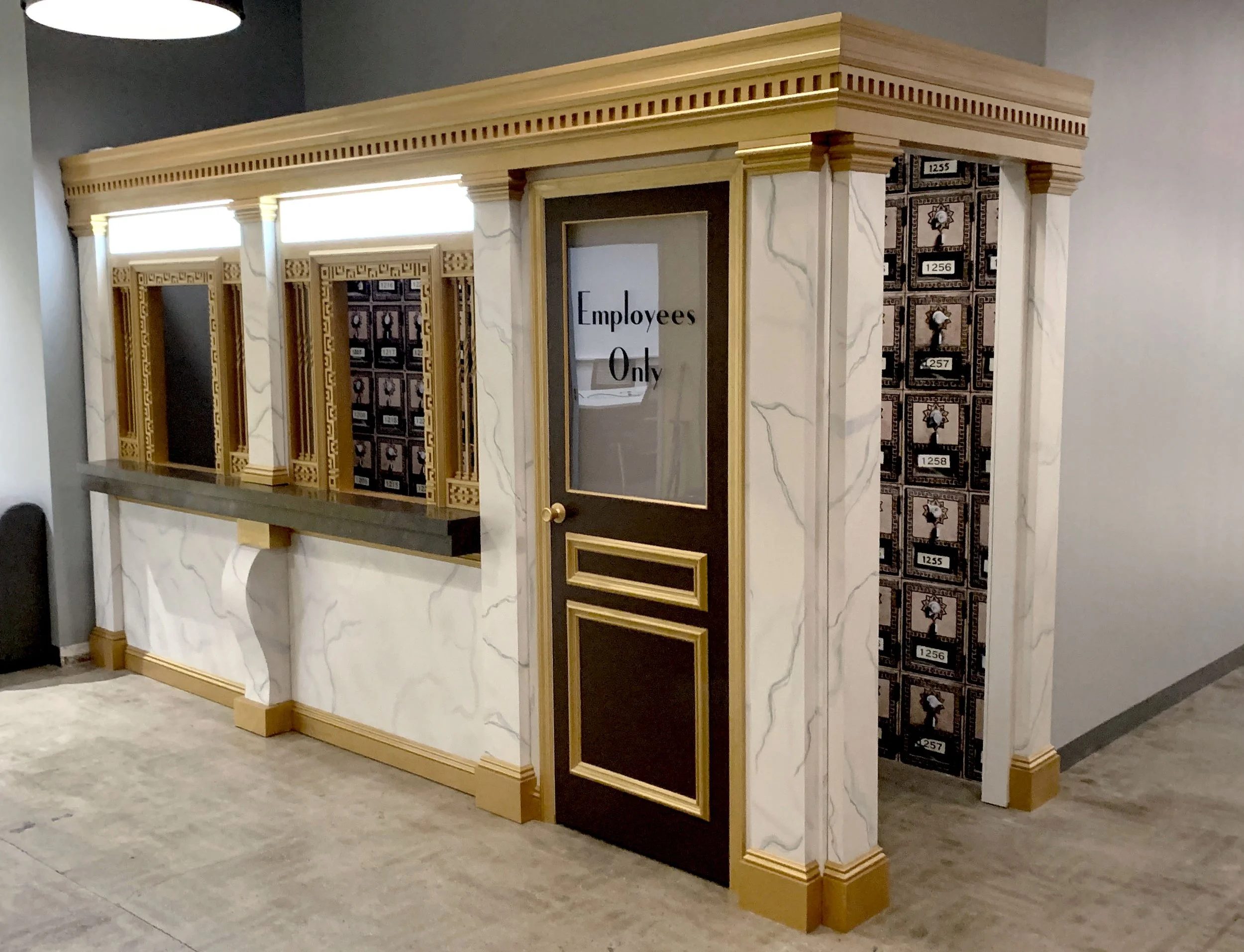 A marble and wood structure with compartments resembling a postal or package locker system, with a door marked "Employees Only."