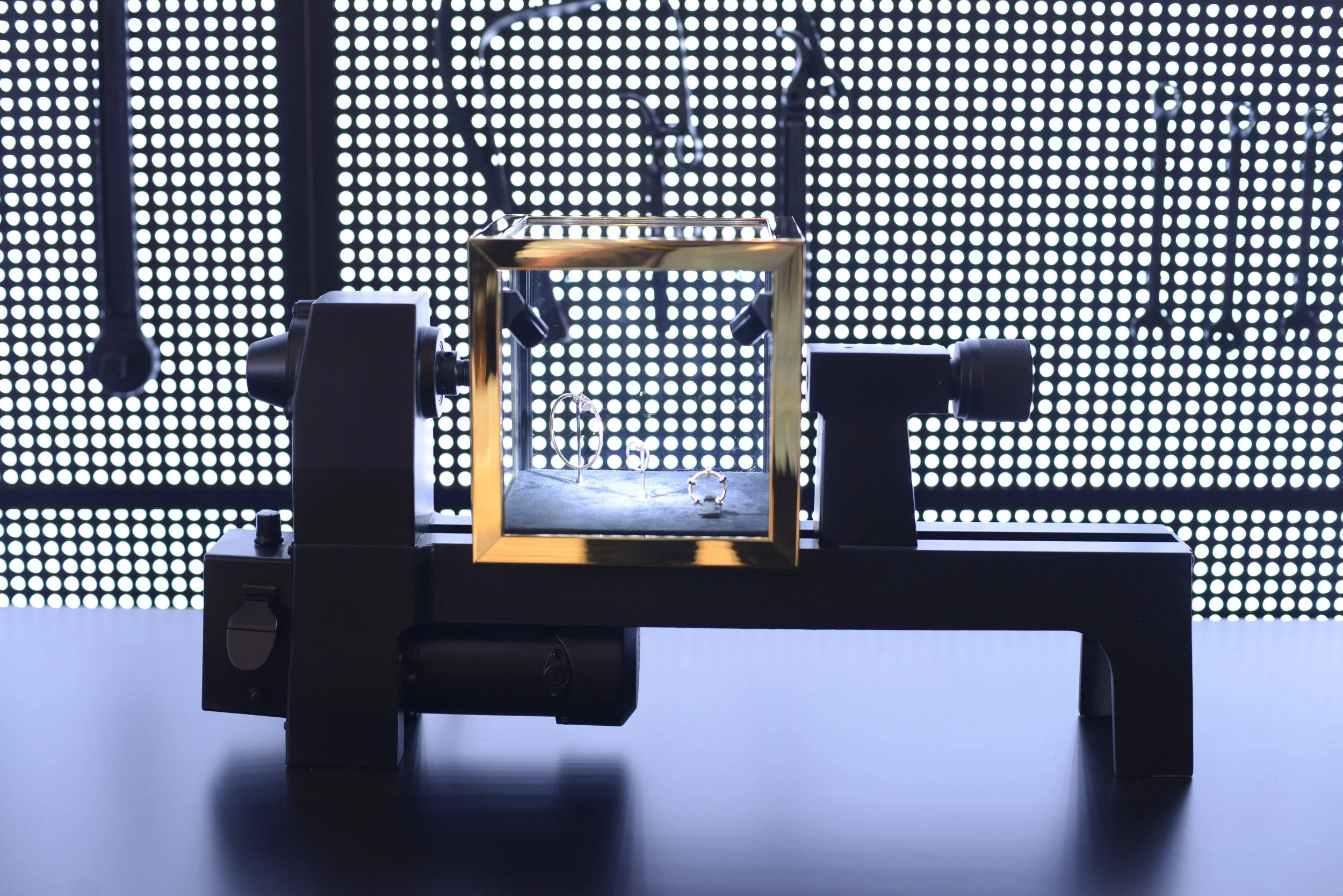 Jewelry display case with earrings and rings, set against a bright, dotted LED background