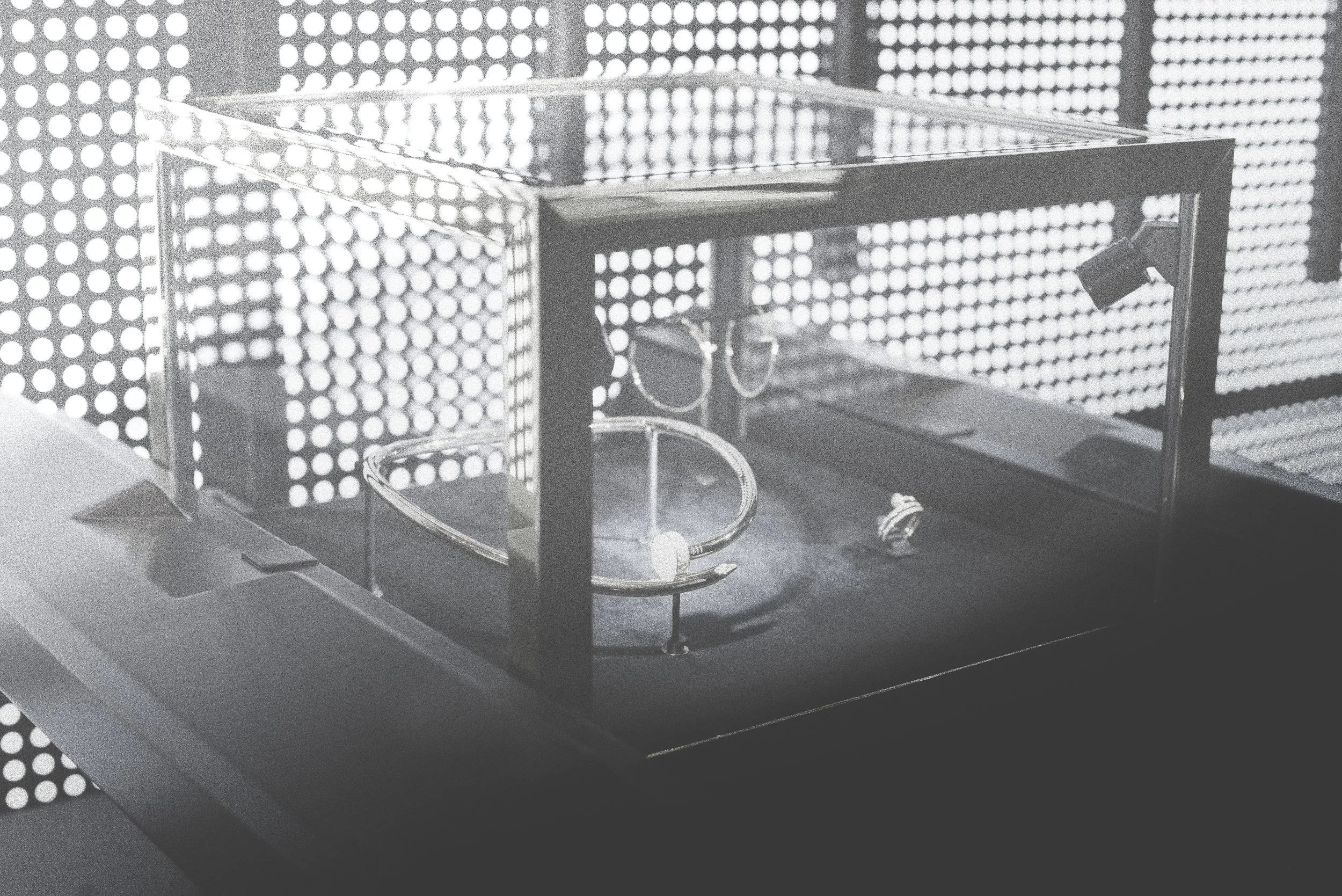 A glass display case with jewelry inside, set against a perforated metal background.
