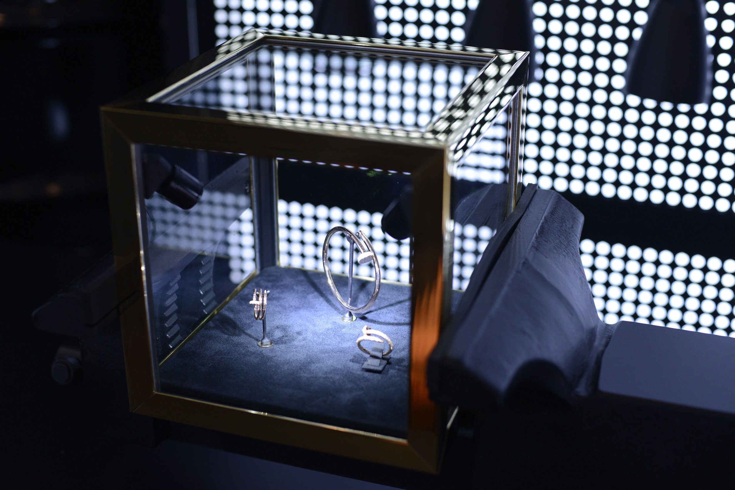 Display case containing gold jewelry with black background and bright white circular lights.