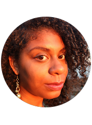 Close-up of a woman with curly hair, gold earrings, and makeup, looking slightly to the side.