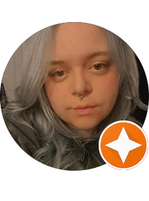 Close-up of a young woman with platinum blonde hair and a septum piercing, looking directly at the camera.