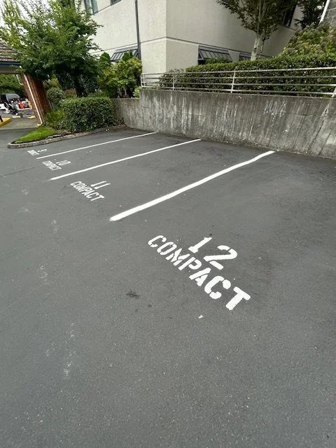 Empty parking spots numbered 11 and 12 with the words 'COMPACT' painted on the ground in a parking lot.