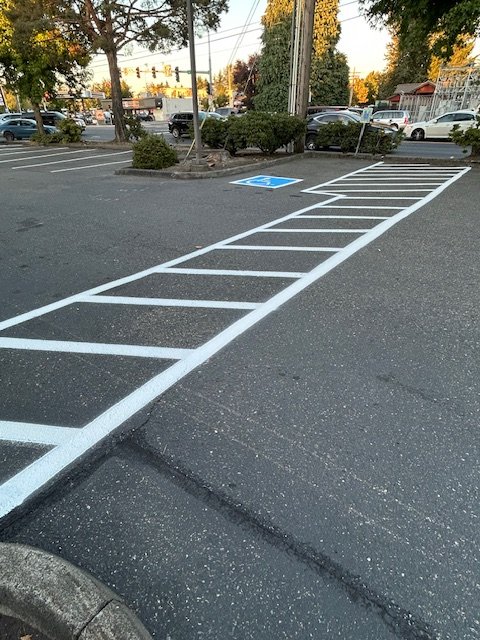 Empty parking space with white diagonal lines and a blue handicapped parking symbol.