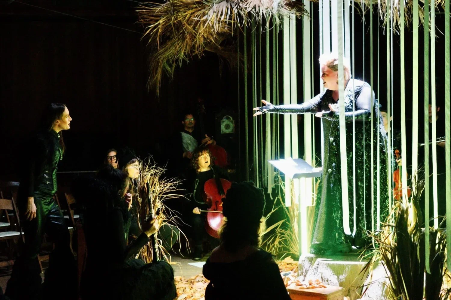 Mezzo-soprano, Jamie Barton, stands on a stage illuminated by light and surrounded by hanging strips of paper.