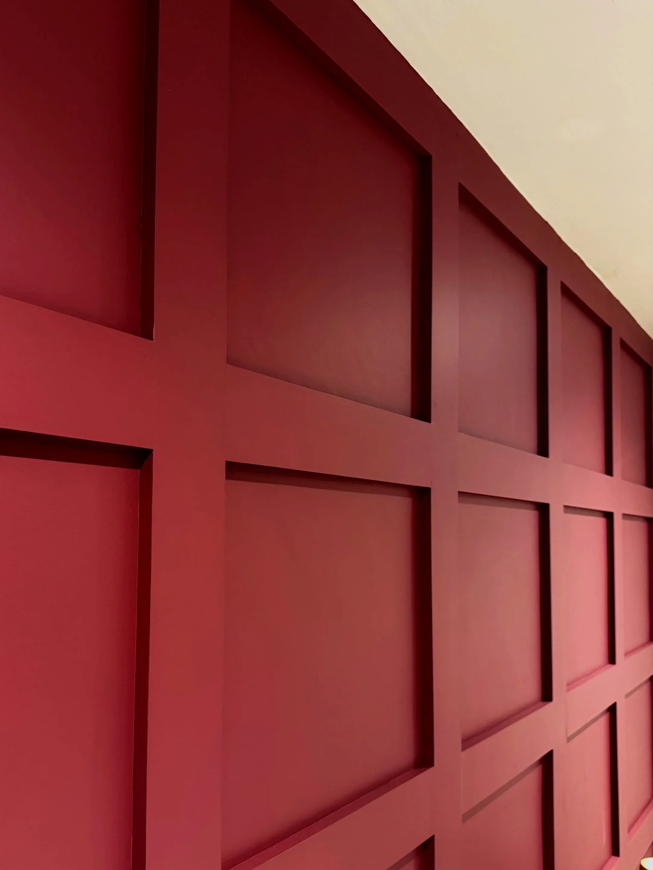 Close-up of a pink wall with a geometric pattern of rectangular and square cutouts.