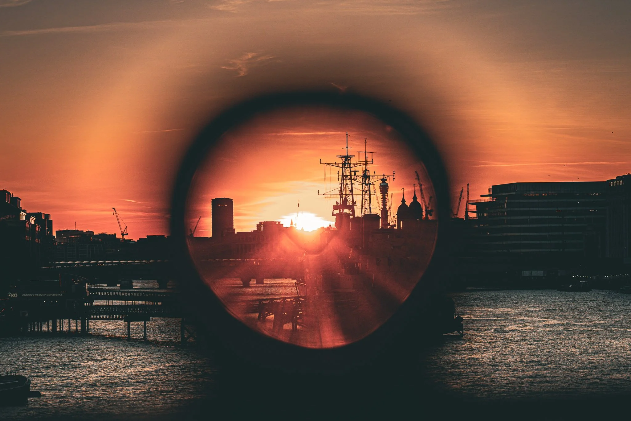 Uitzicht over de stad met schepen en gebouwen, gezien door een verrekijker tijdens zonsondergang in Londen.