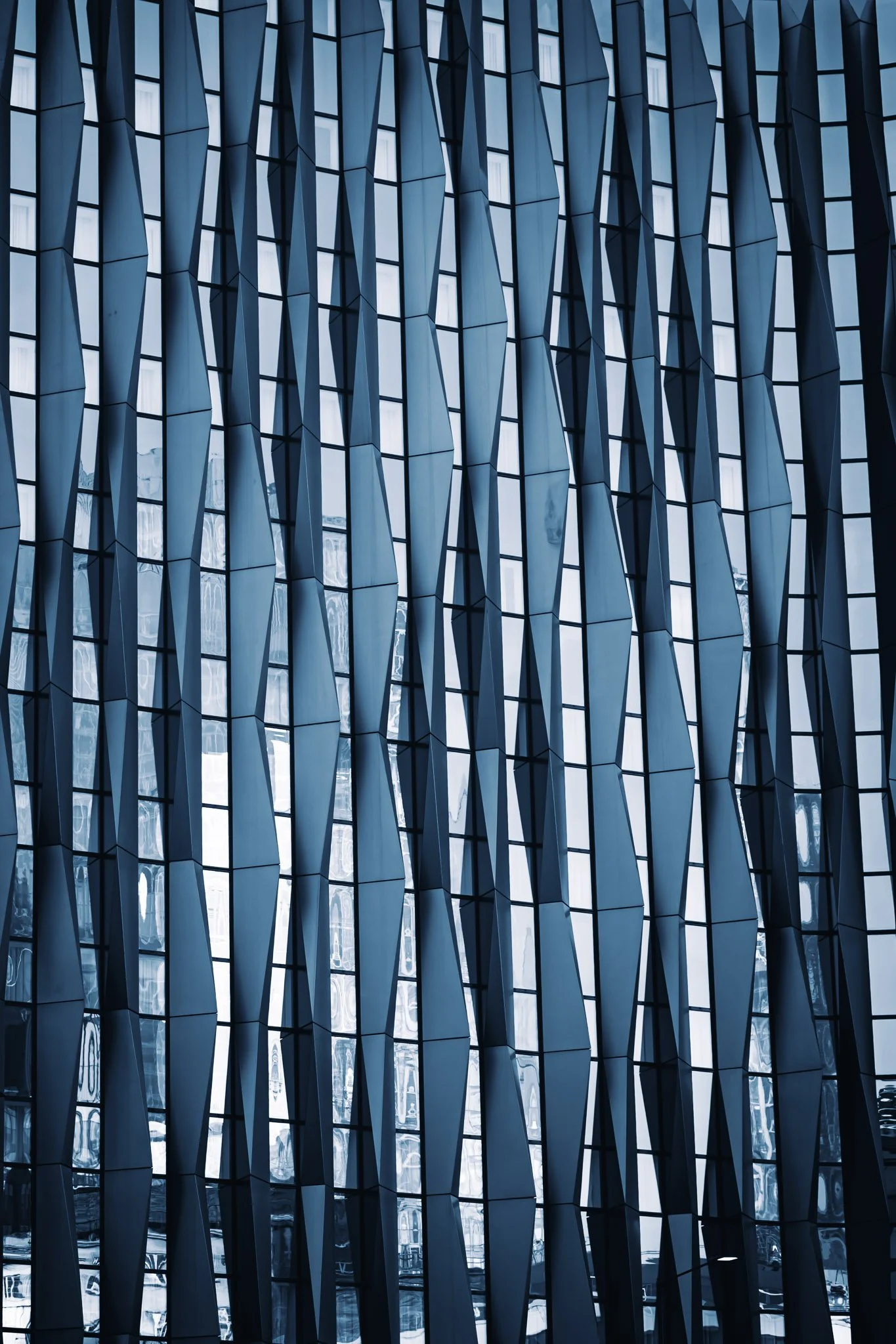 Een modern gebouwengevel met een patroon van glazen ramen en metalen lamellen.