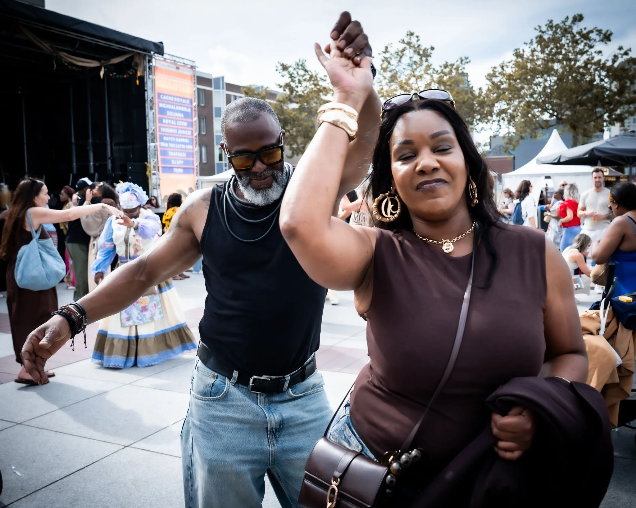 Mensen dansen en je ziet een man en een vrouw hand in hand dansen op een buitenfestival