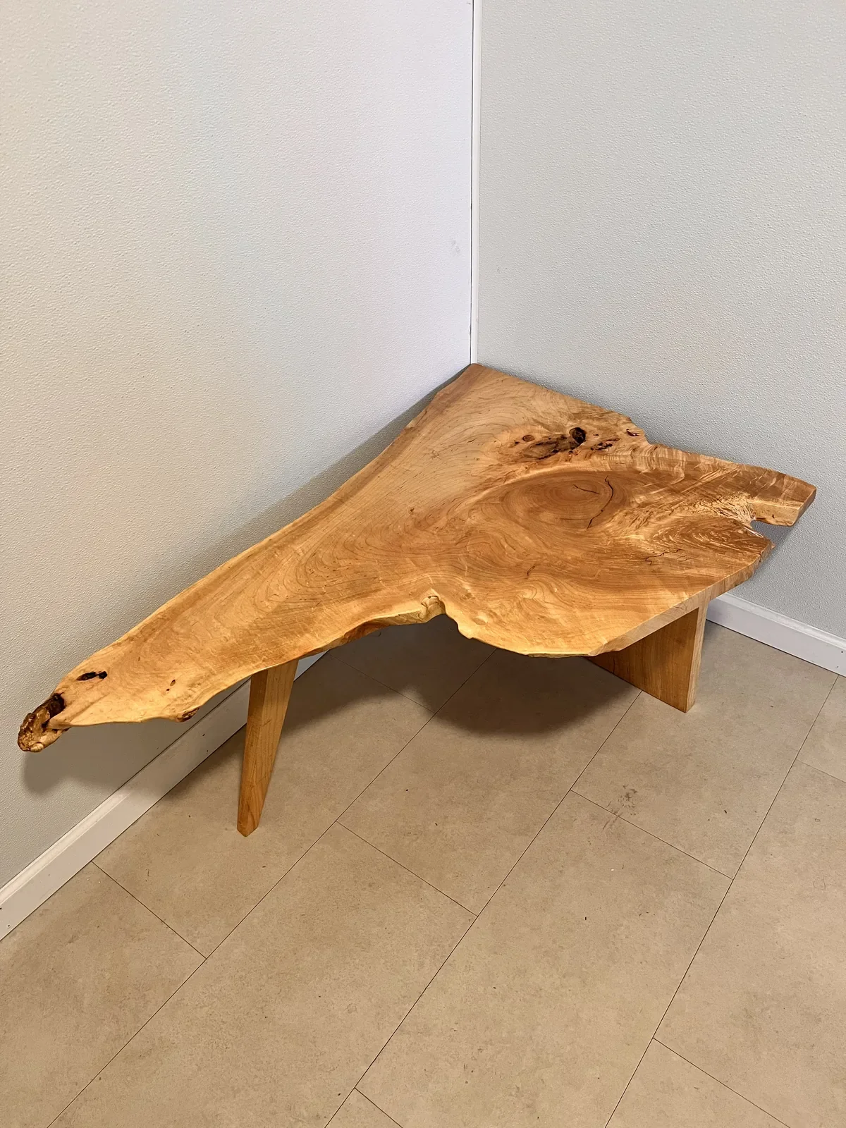 Highly figured burl and crotch-grain hardwood coffee table with dramatic swirling grain pattern, on simple wood legs