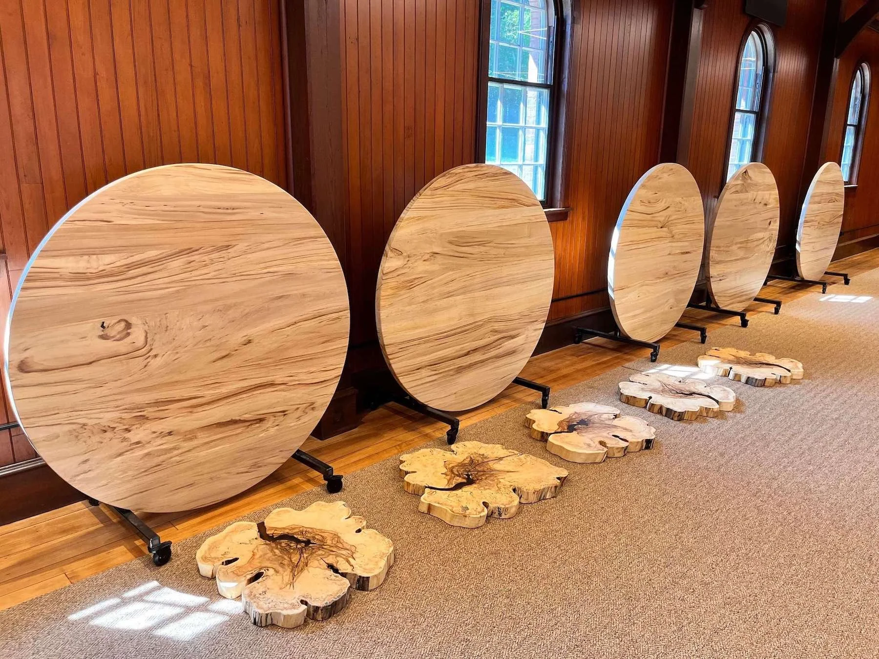 Multiple large, round sycamore tables with a polished surface, in a gathering space.