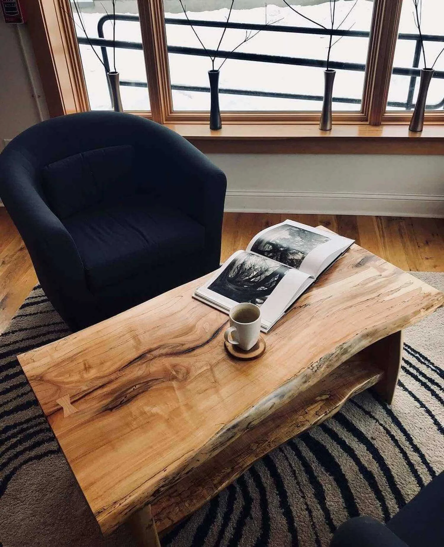maple coffee table with dark grain and beautiful spaulting with a steaming cup of coffee and a snowy view out the window.