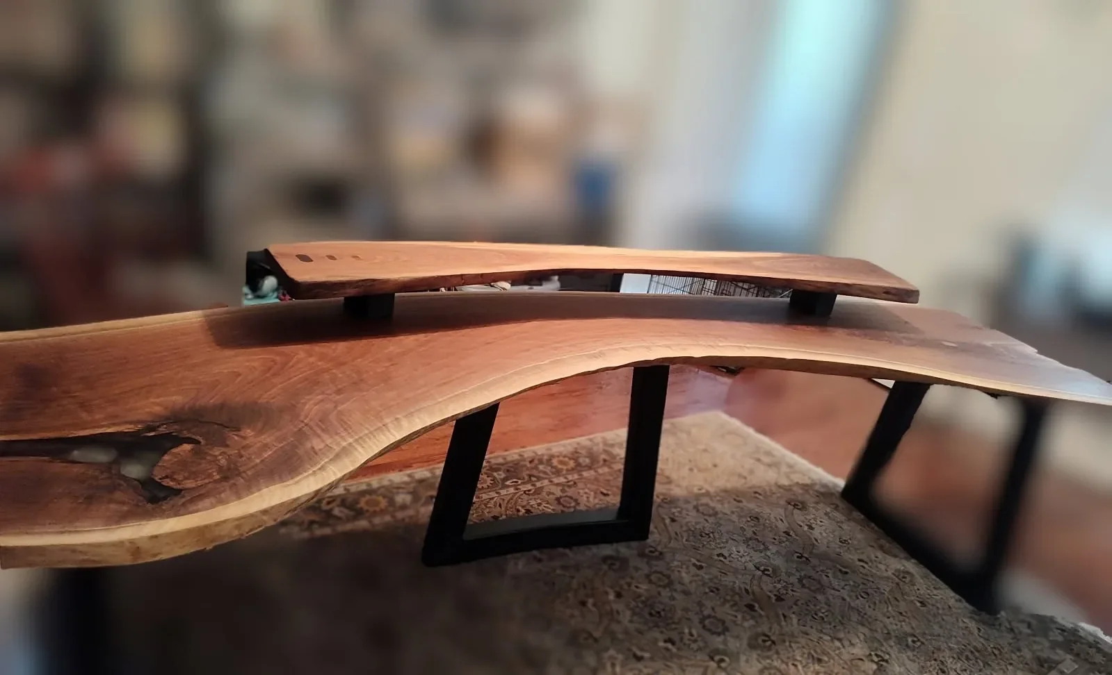 Close-up detail of live edge walnut countertop showing rich grain pattern and natural bark edge on black metal legs