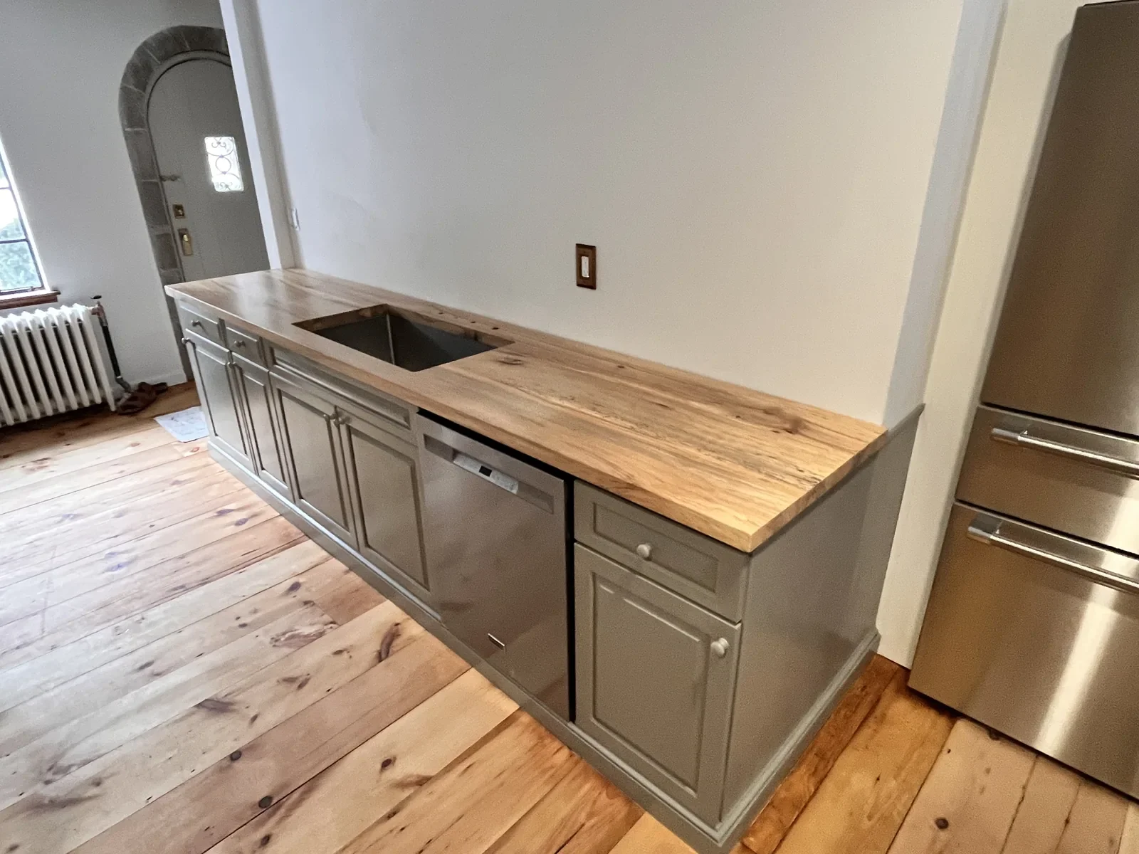 Hardwood butcher block countertop with undermount sink installed in a gray painted kitchen during a historic home renovation