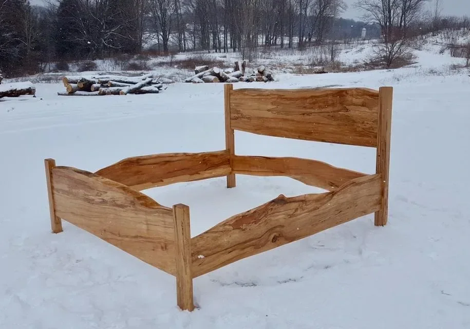 Full live edge hardwood bed frame — headboard, footboard, and side rails — photographed outdoors at the Vermont Tree Goods property in winter