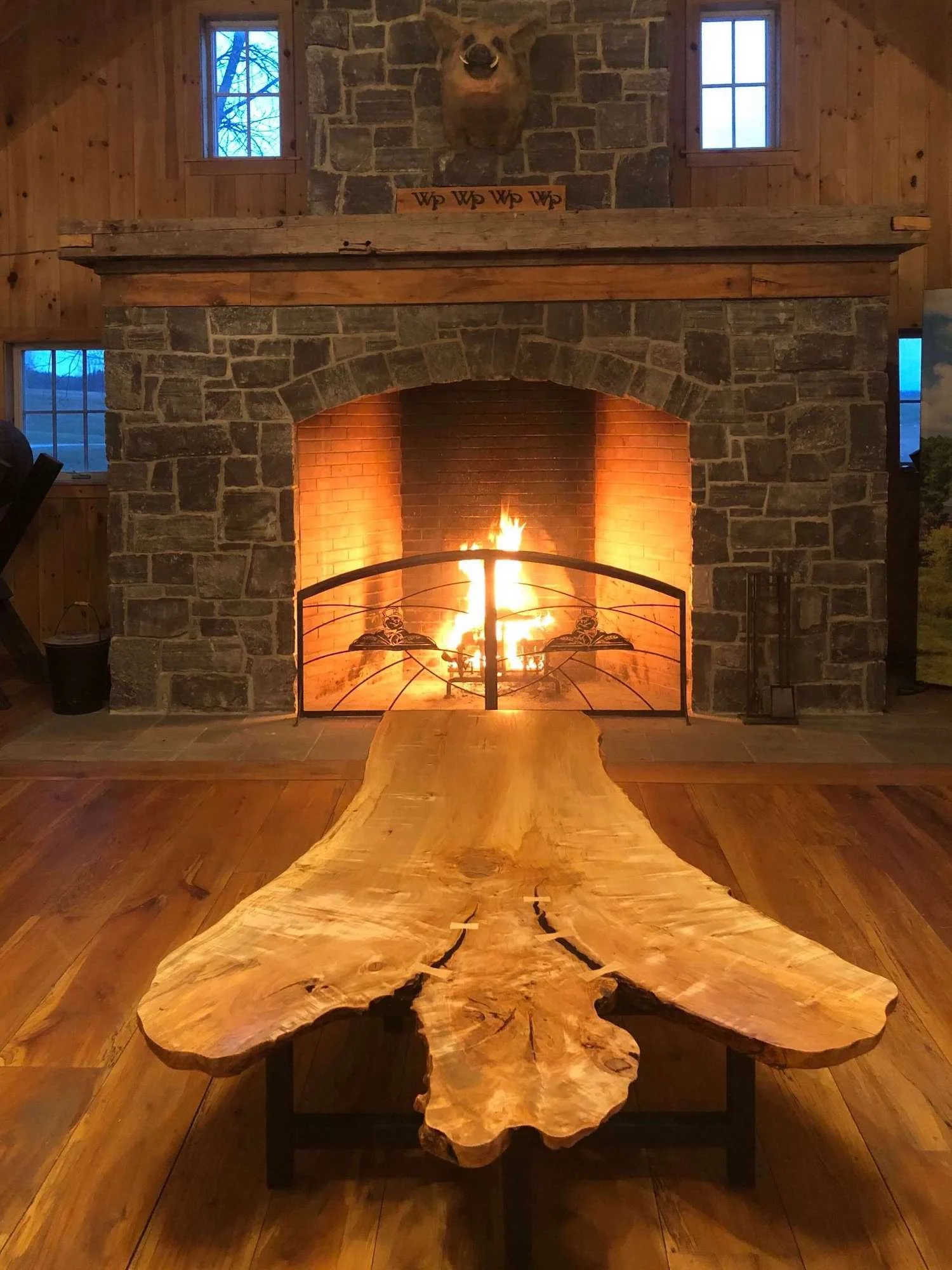 A beautiful live edge maple table that splits into three, with handcrafted bowties in the table, displayed in front an old stone fire place at Whistle Pig Whiskey's tasting room.