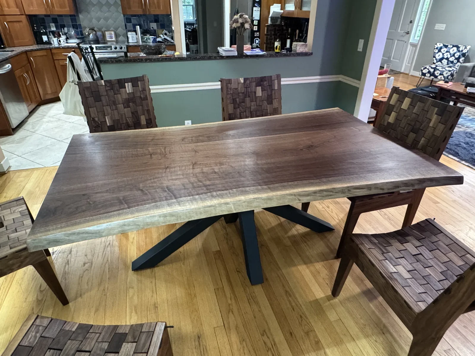 Dark walnut live edge dining table with a black starburst base, installed in a residential dining room