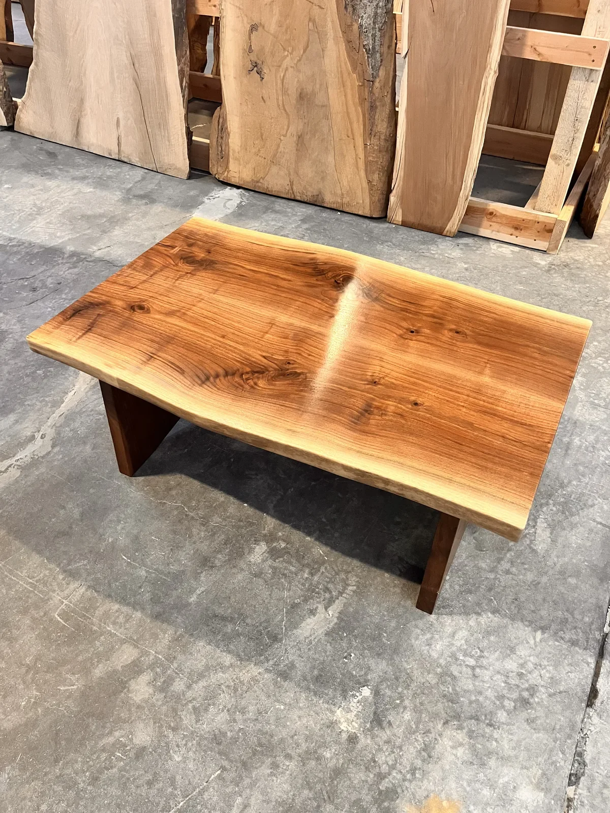 Live edge hardwood coffee table with wood panel legs, displayed in the Vermont Tree Goods showroom