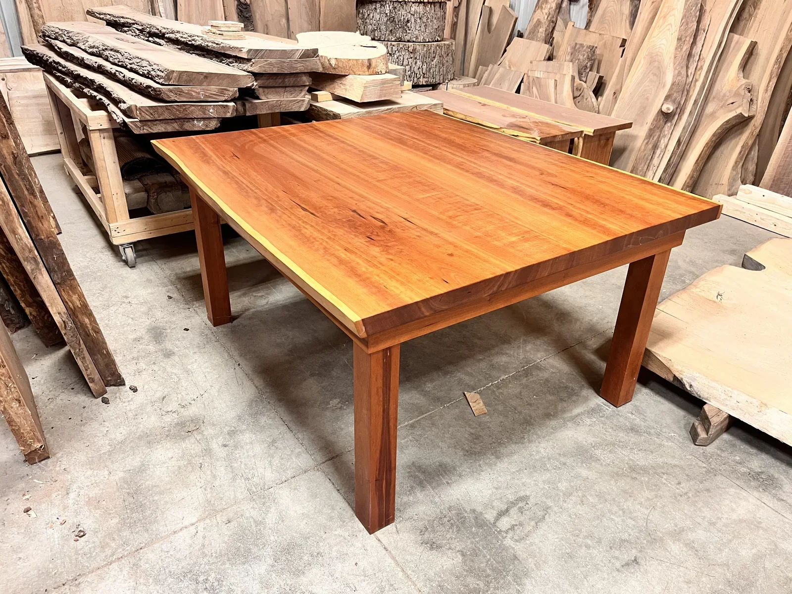 Warm-toned hardwood dining table with solid wood legs, photographed in the Vermont Tree Goods workshop