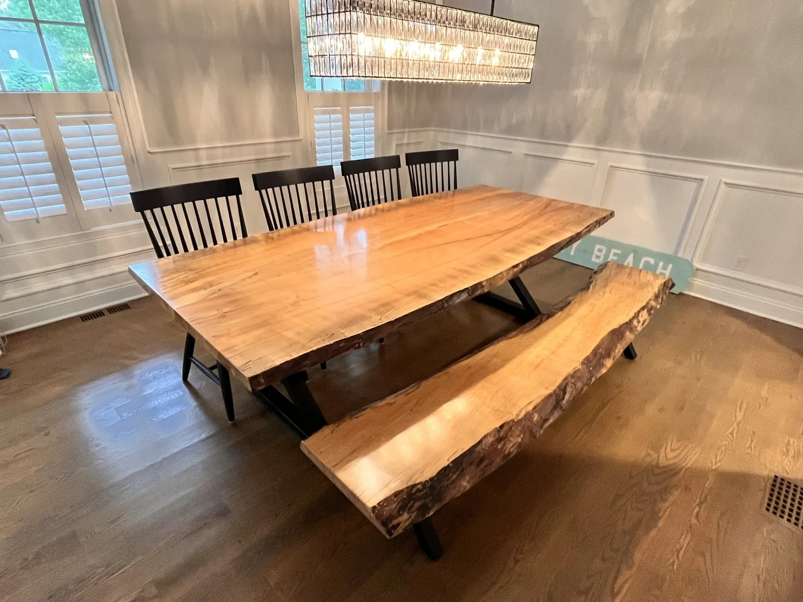 Custom live edge dining table with matching bench, installed in a Connecticut home dining room with wainscoting and chandelier