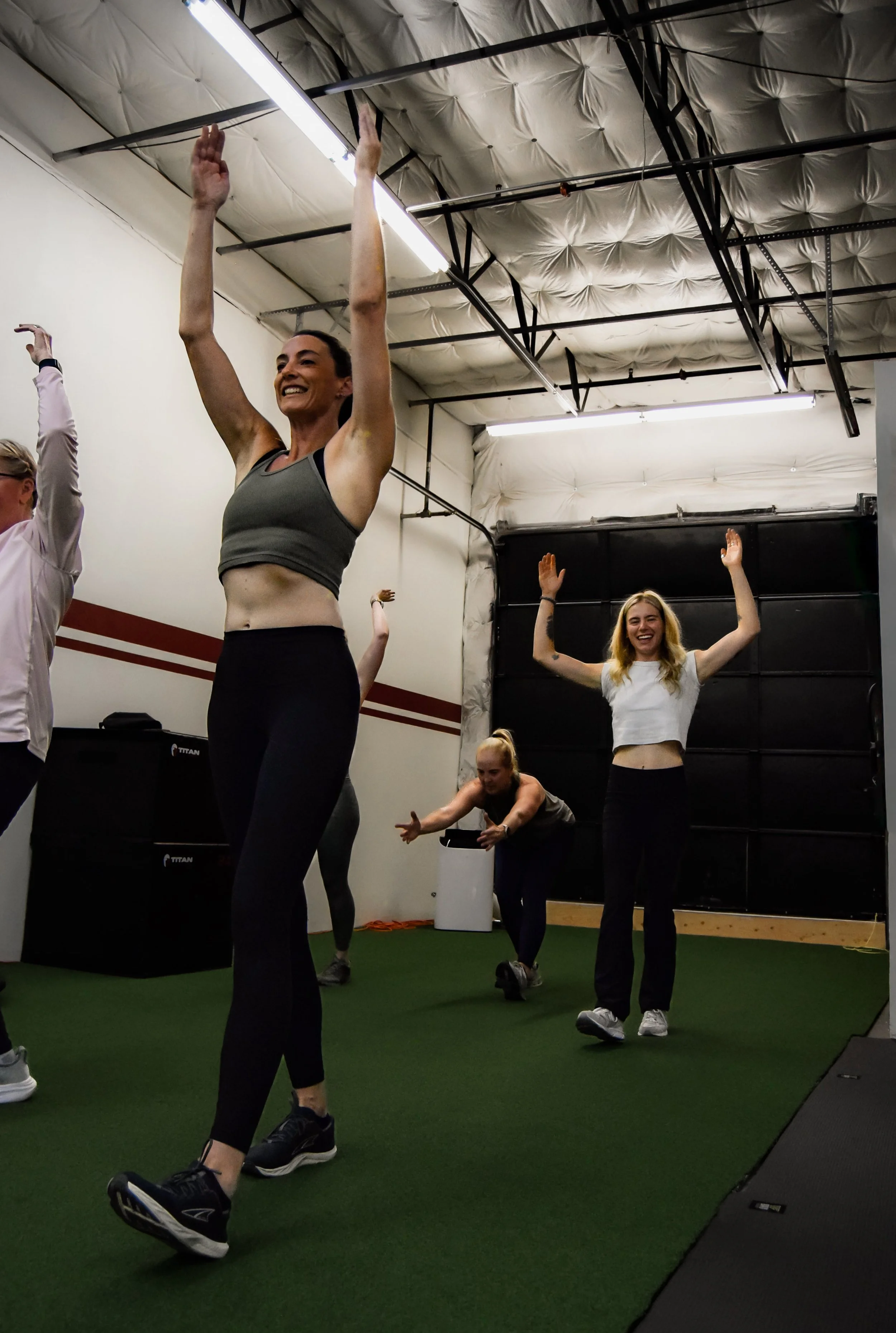 Kettlebells and a medicine ball on a gym floor with people exercising in the background.