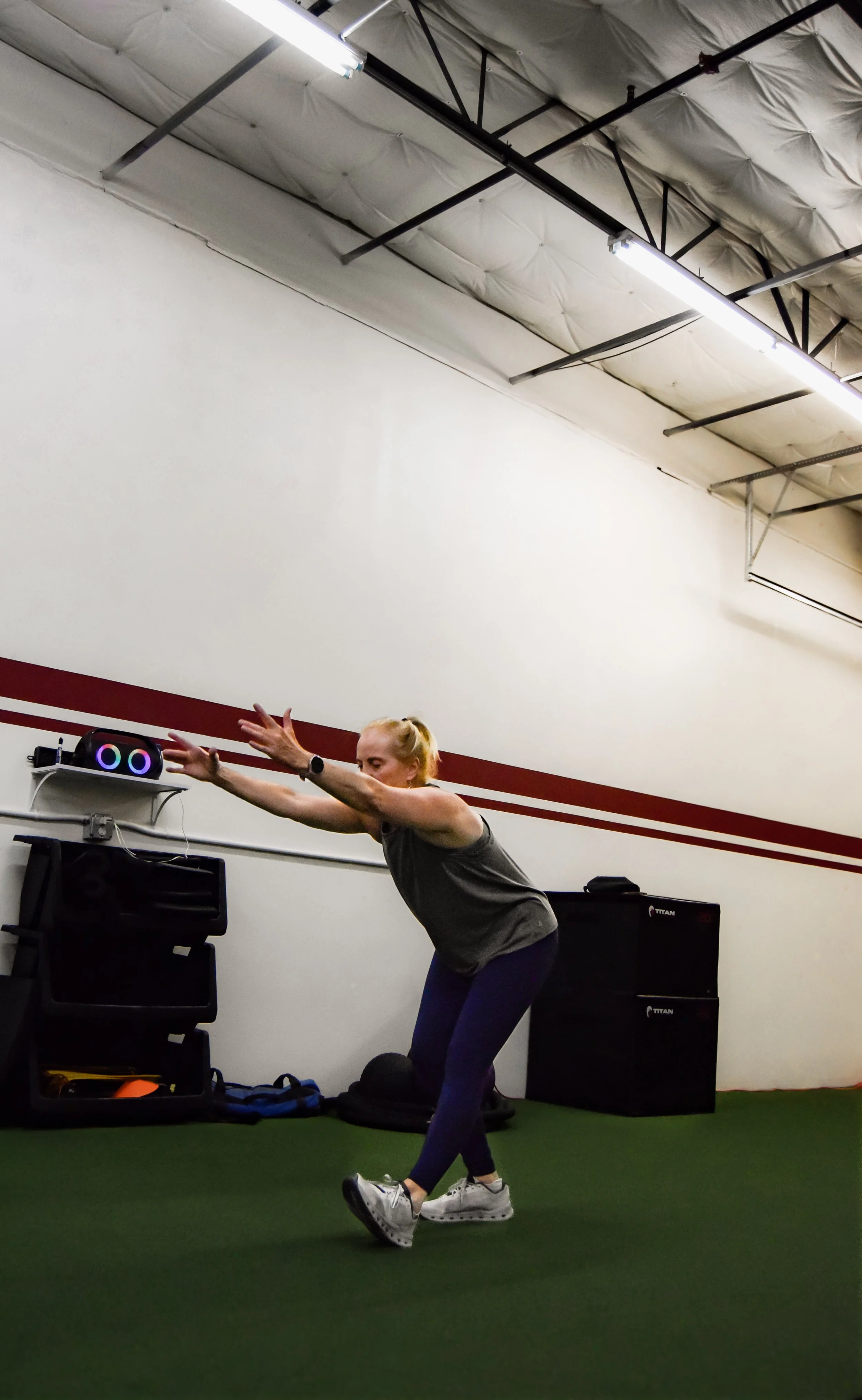 A woman lifting a barbell in a gym, surrounded by workout equipment and weights.