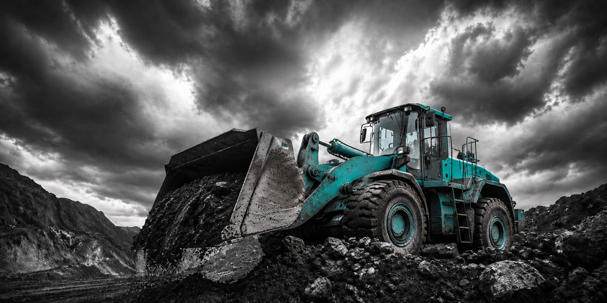 A large blue bulldozer moving dirt and rocks on rugged terrain under a stormy sky.