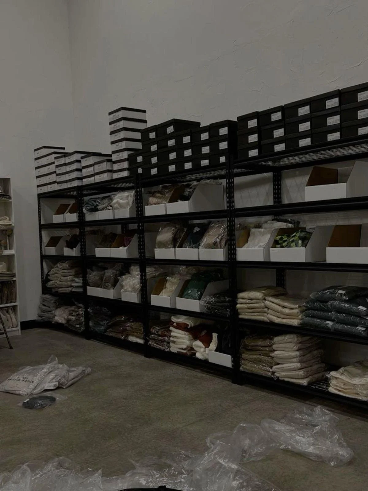 Metal shelving unit filled with packaged textiles, blankets, or linens, in a storage room.